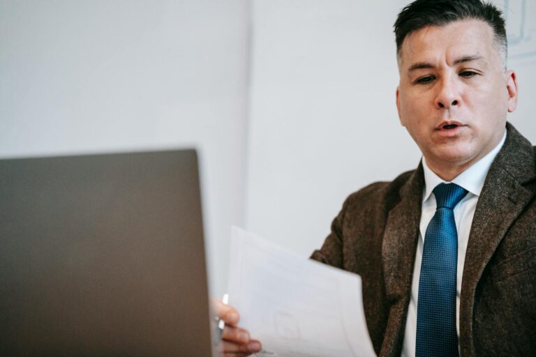 A focused lecturer in a suit, using a laptop for an online session.